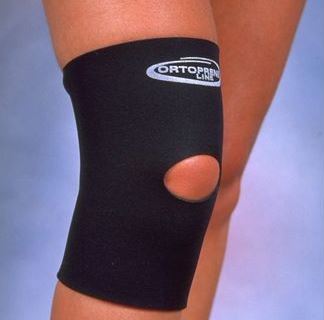 Joelheira com Orifício Joelheira de neoprene Ortocenter, na cor preta, com orifício para a rótula. A imagem mostra a joelheira esticada, destacando o orifício e o design de cano curto.